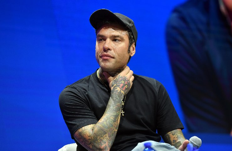 Fedez ascolta seduto sulla sedia