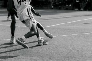 Immagine in bianco e nero che mostra la parte inferiore di due giocatori di basket mentre sono in campo