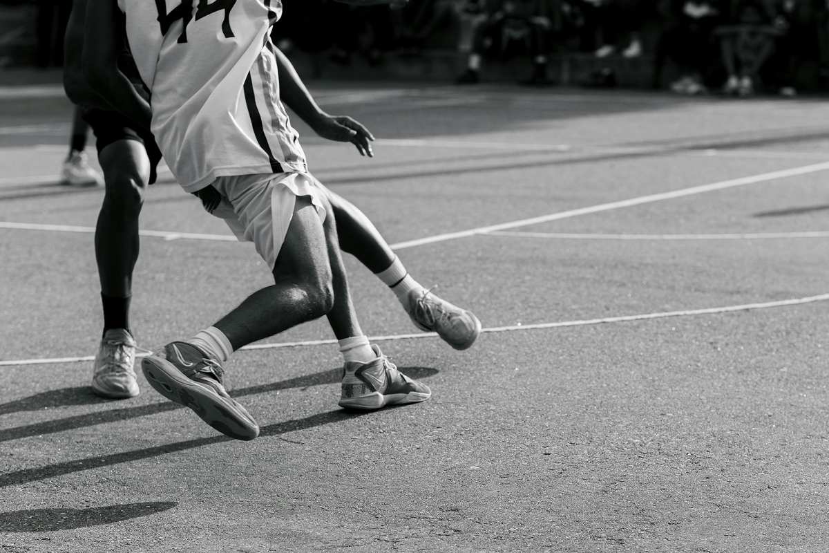 Immagine in bianco e nero che mostra la parte inferiore di due giocatori di basket mentre sono in campo